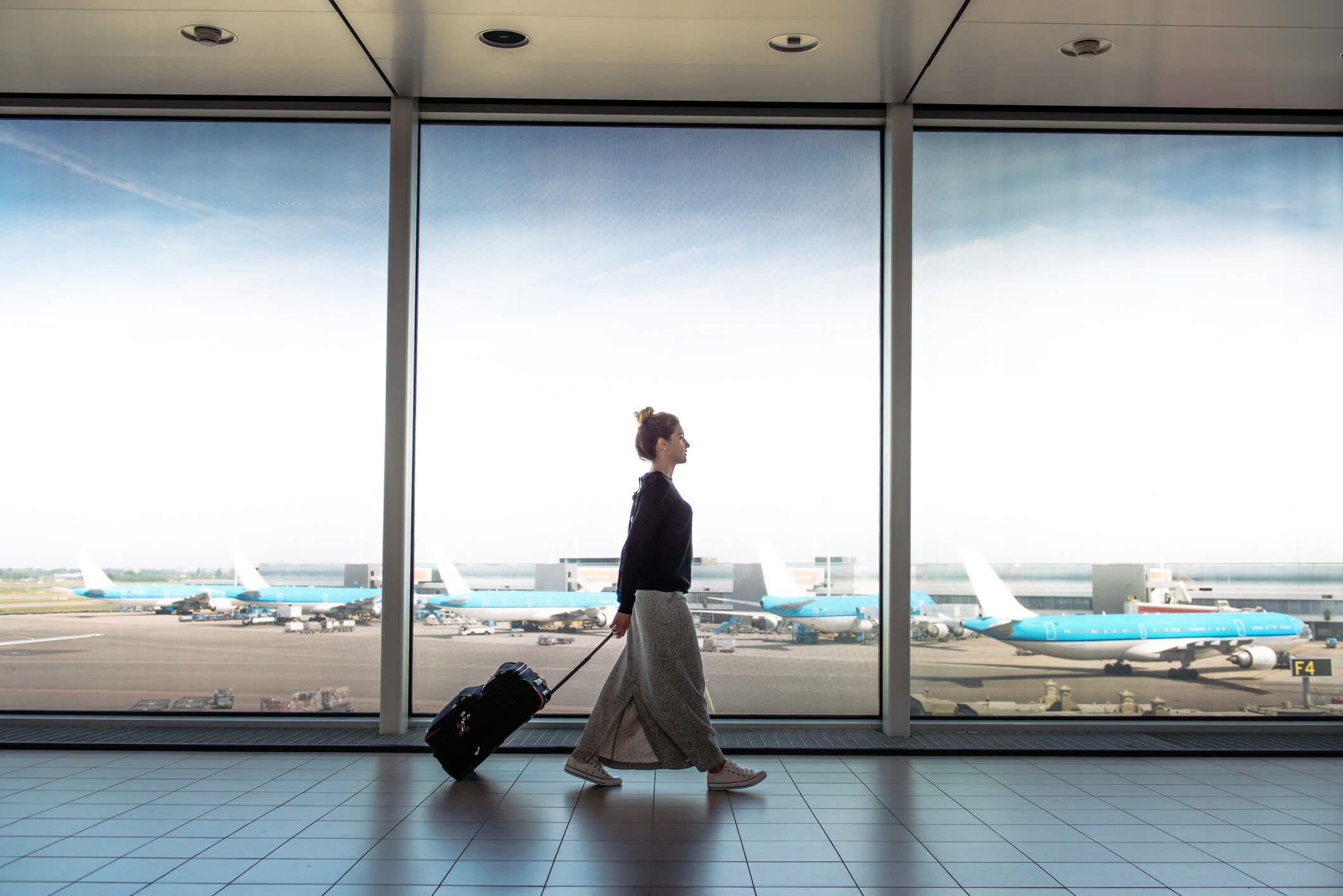 a woman holding her suitcase while walking at the airport