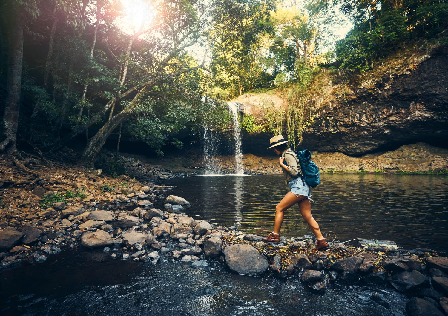 a woman walking in the forest near a waterfall