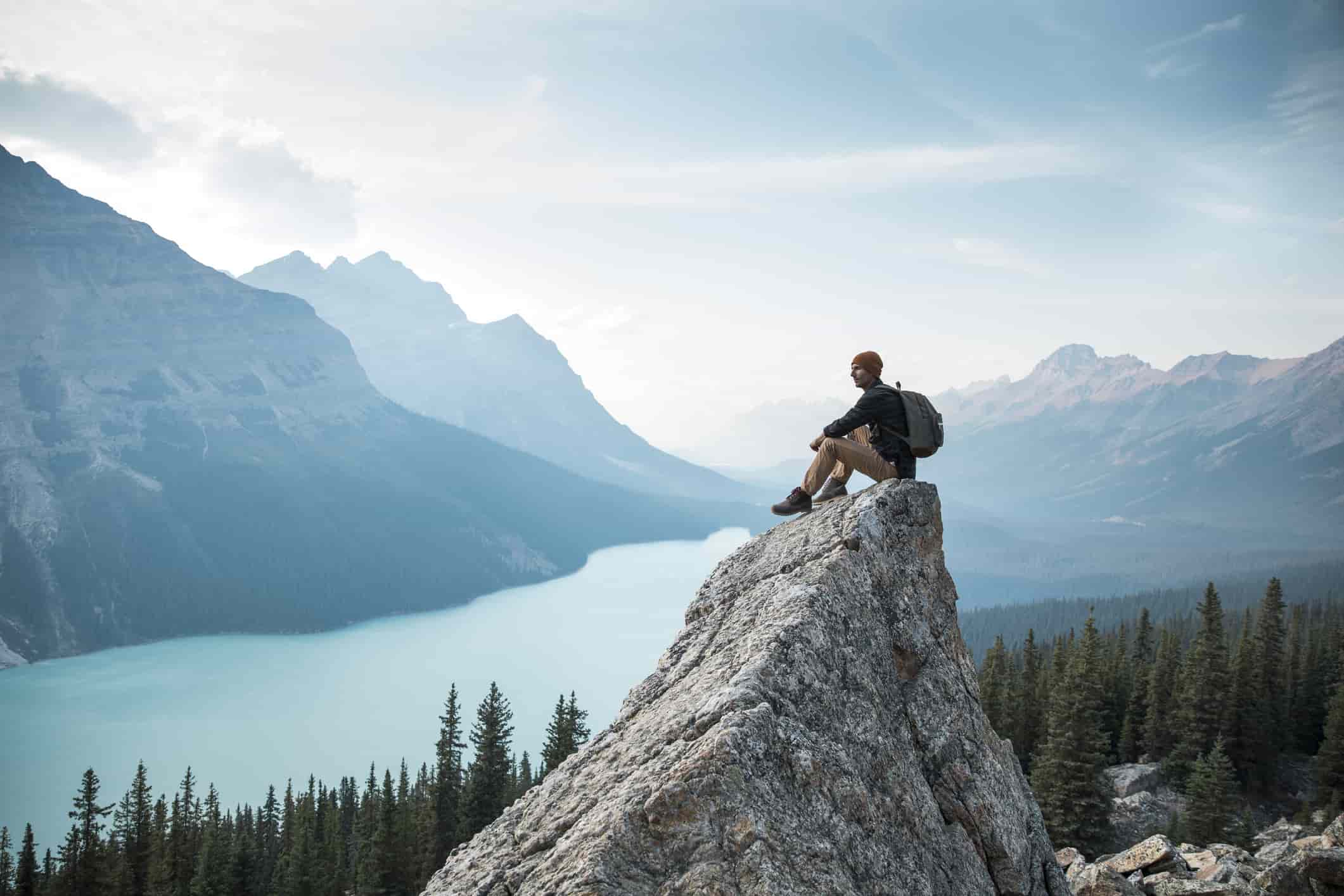 man sitting on rock with a beautiful view of the lake