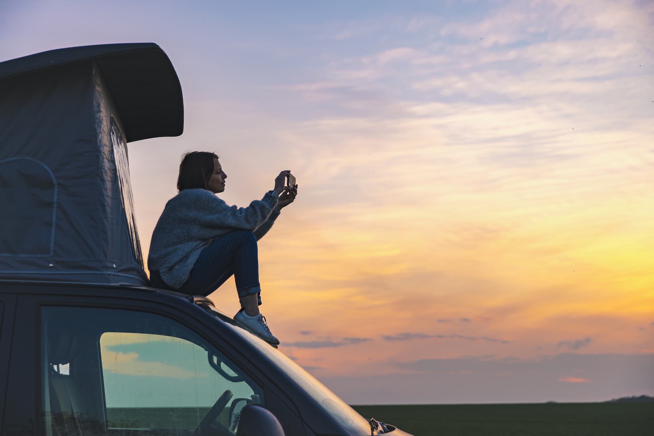 a woman photographing the sunset