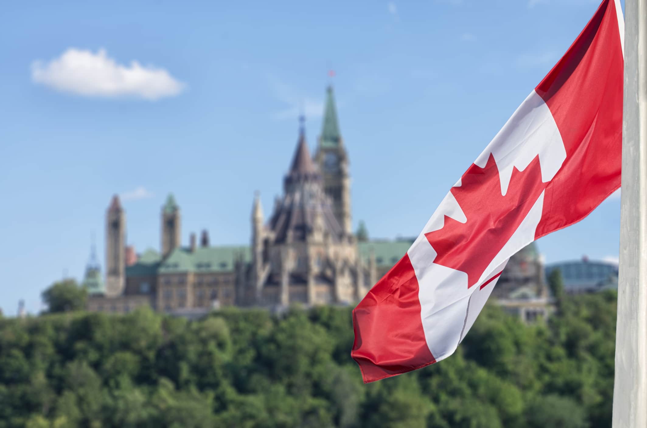 Canadian flag waving with Parliament Buildings hill and Library