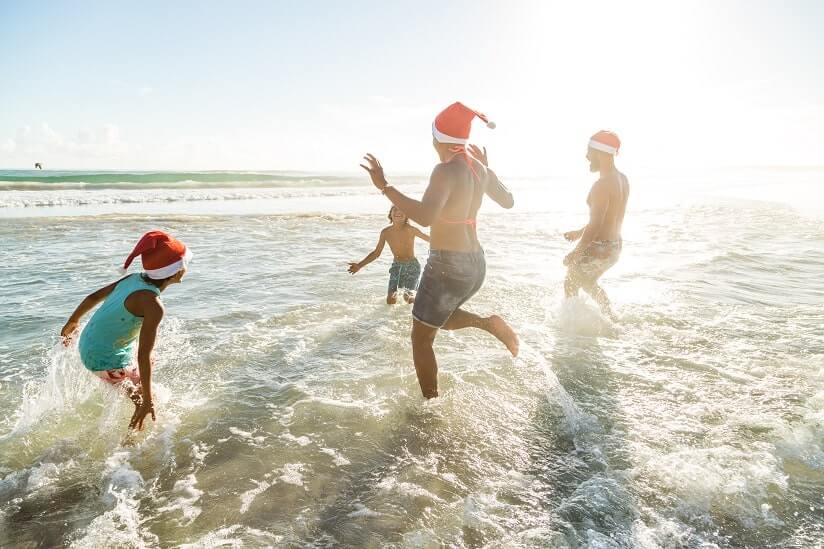 people having fun in the sea while wearing Christmas hats
