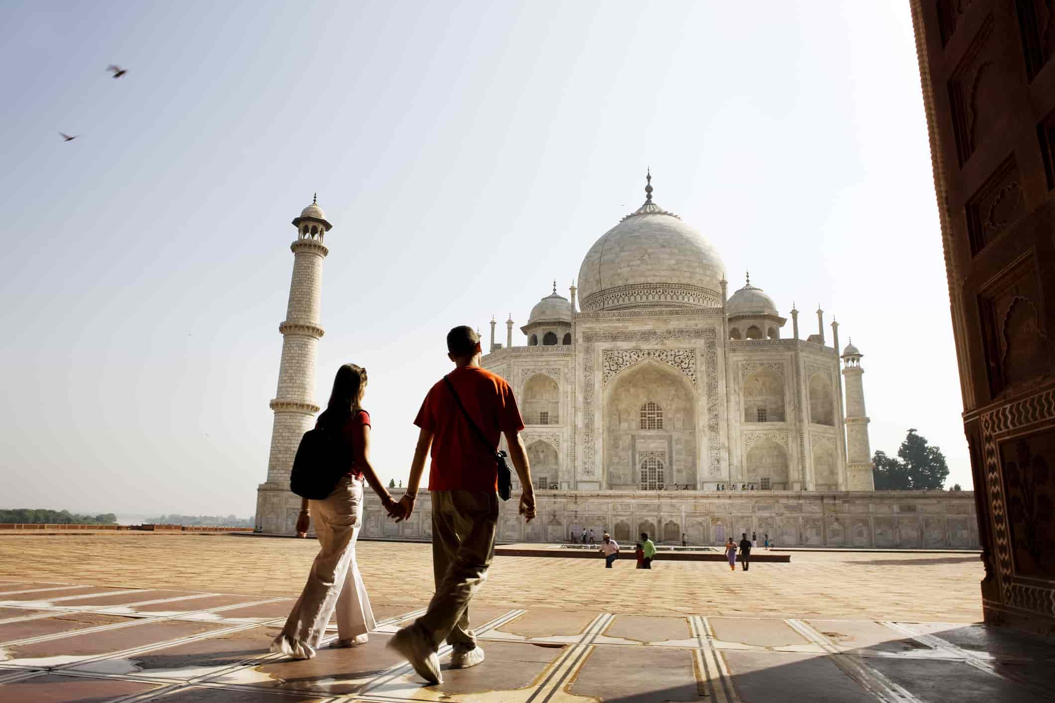 a young couple walking in front of the Taj Mahal
