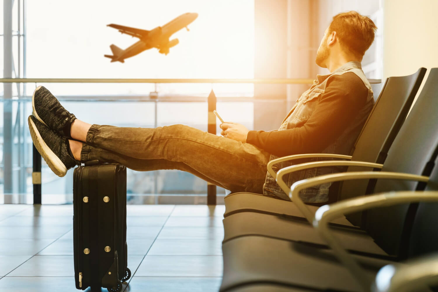 a traveller waiting at an airport and looking at a plane