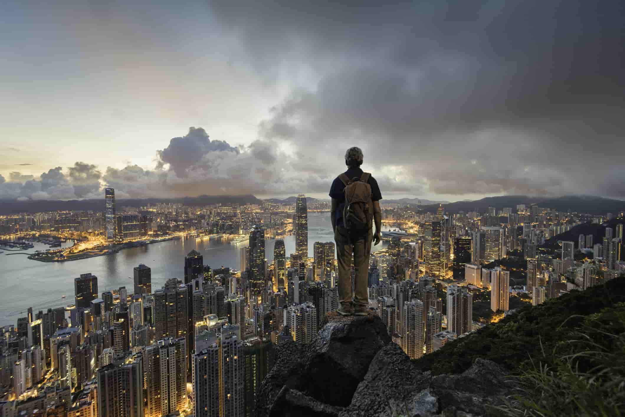 a man standing on a rock overlooking Hong Kong skyline