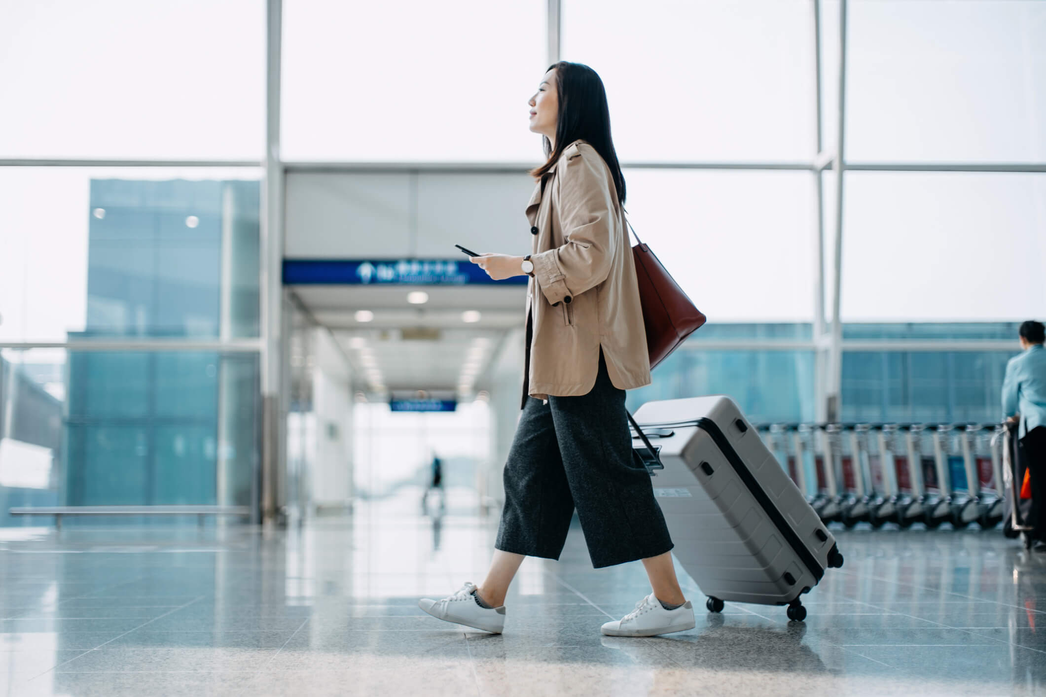 a woman walking at an airport with her suitcase