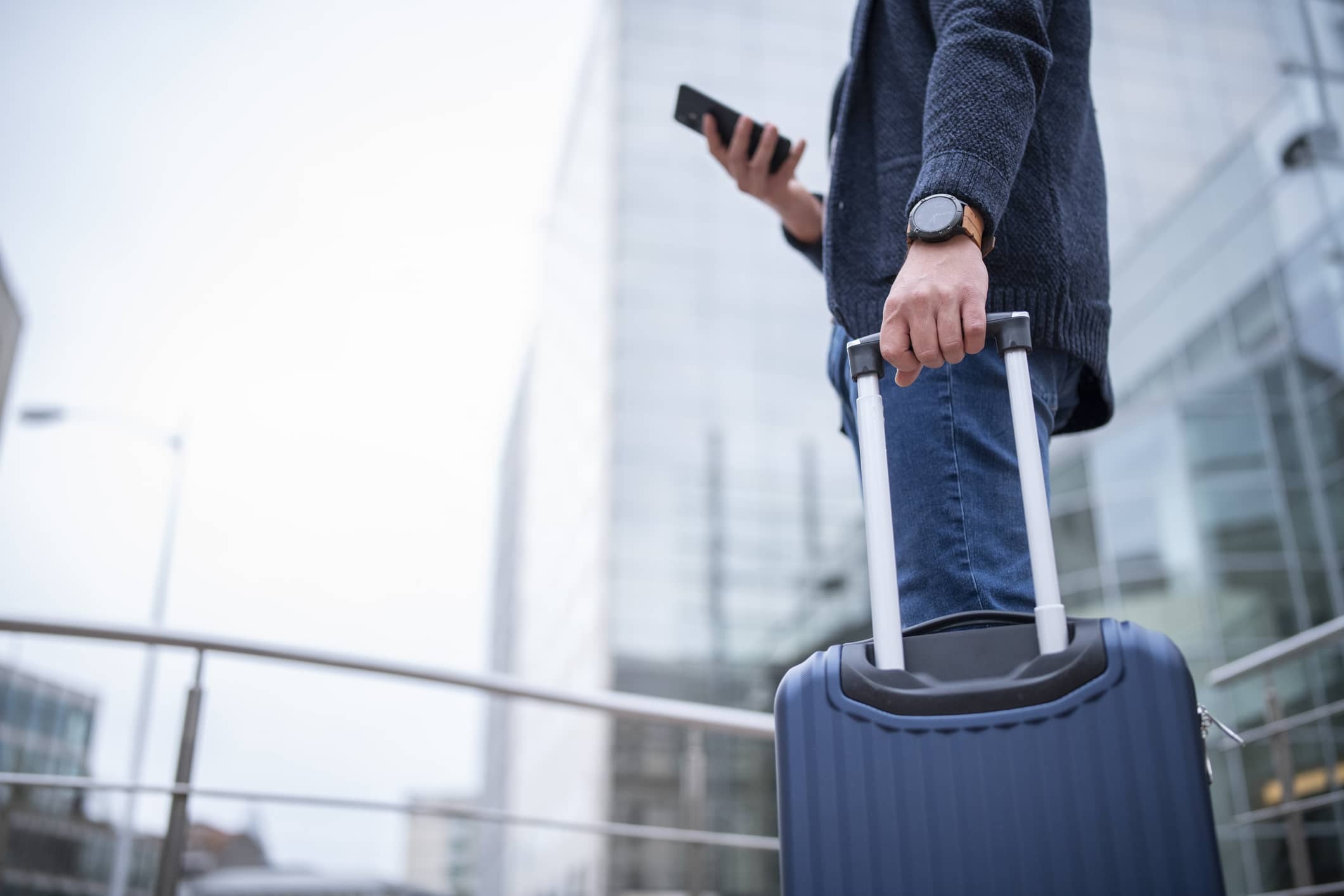 a businessman using his smartphone and holding his suitcase