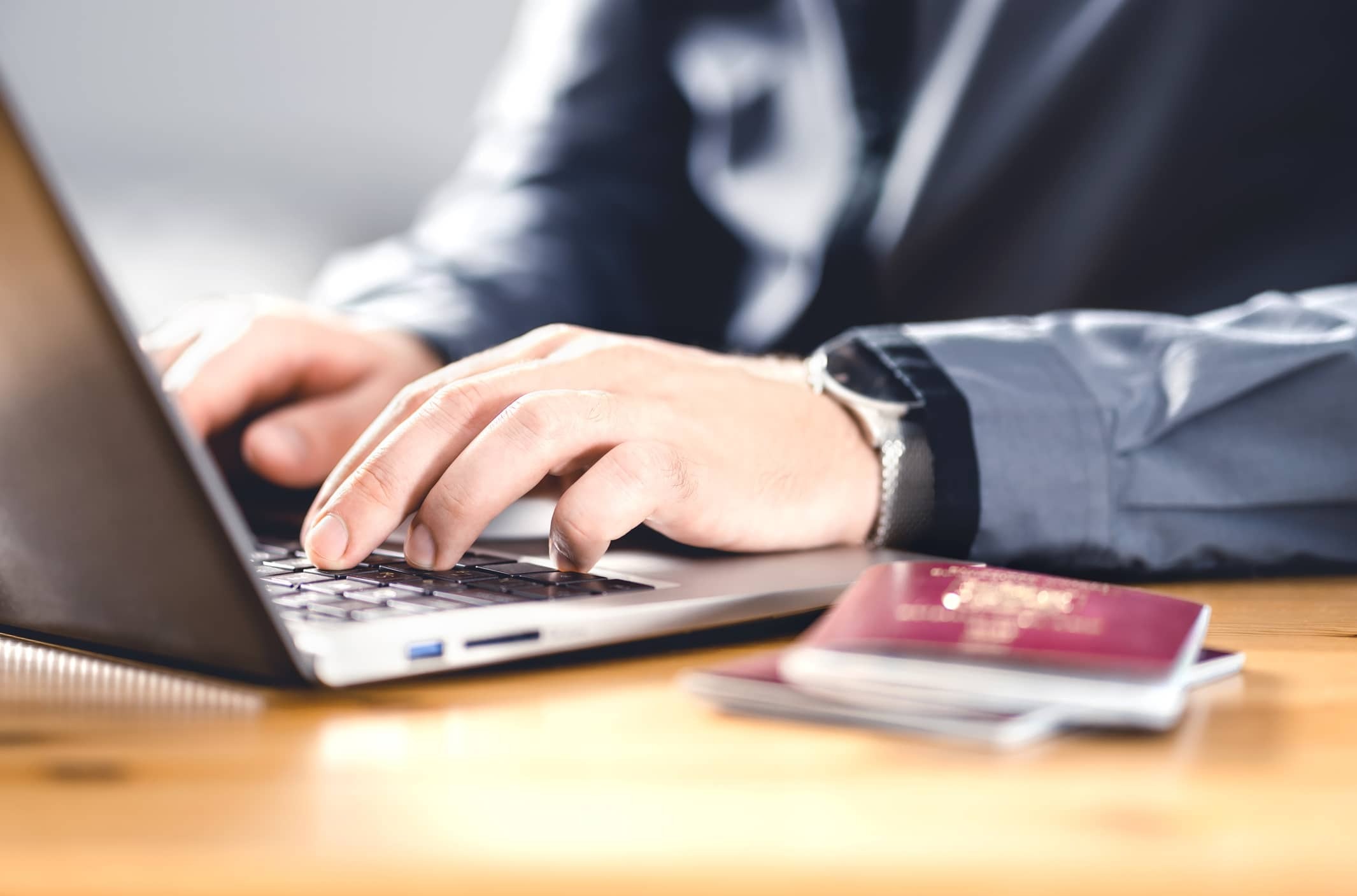 a passport and a person working on his laptop